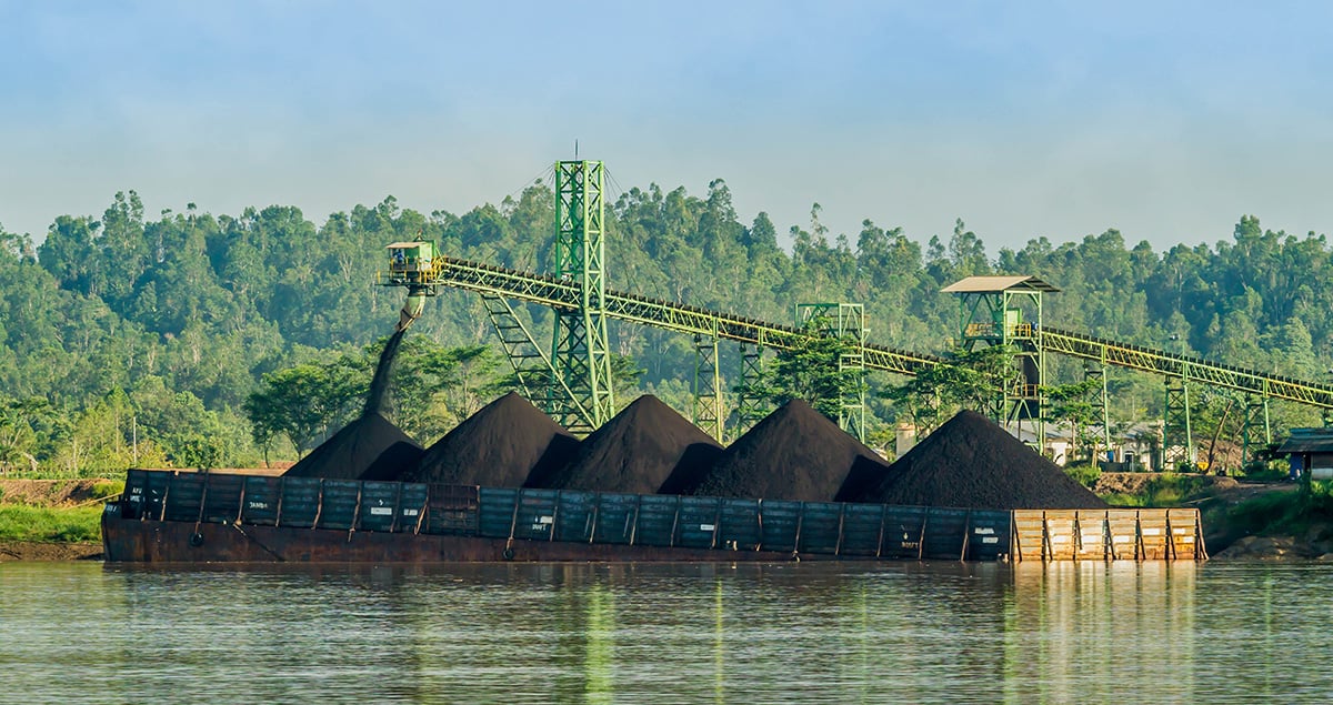 A coal barge is filled from a riverside stockpile in the outback of Borneo, Indonesia